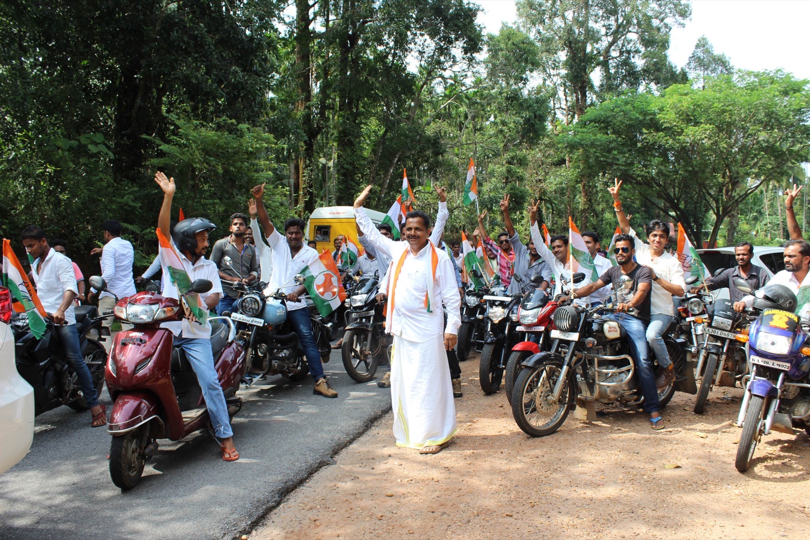 Hundreds of riders with flags line a road at the Karkala bike rally